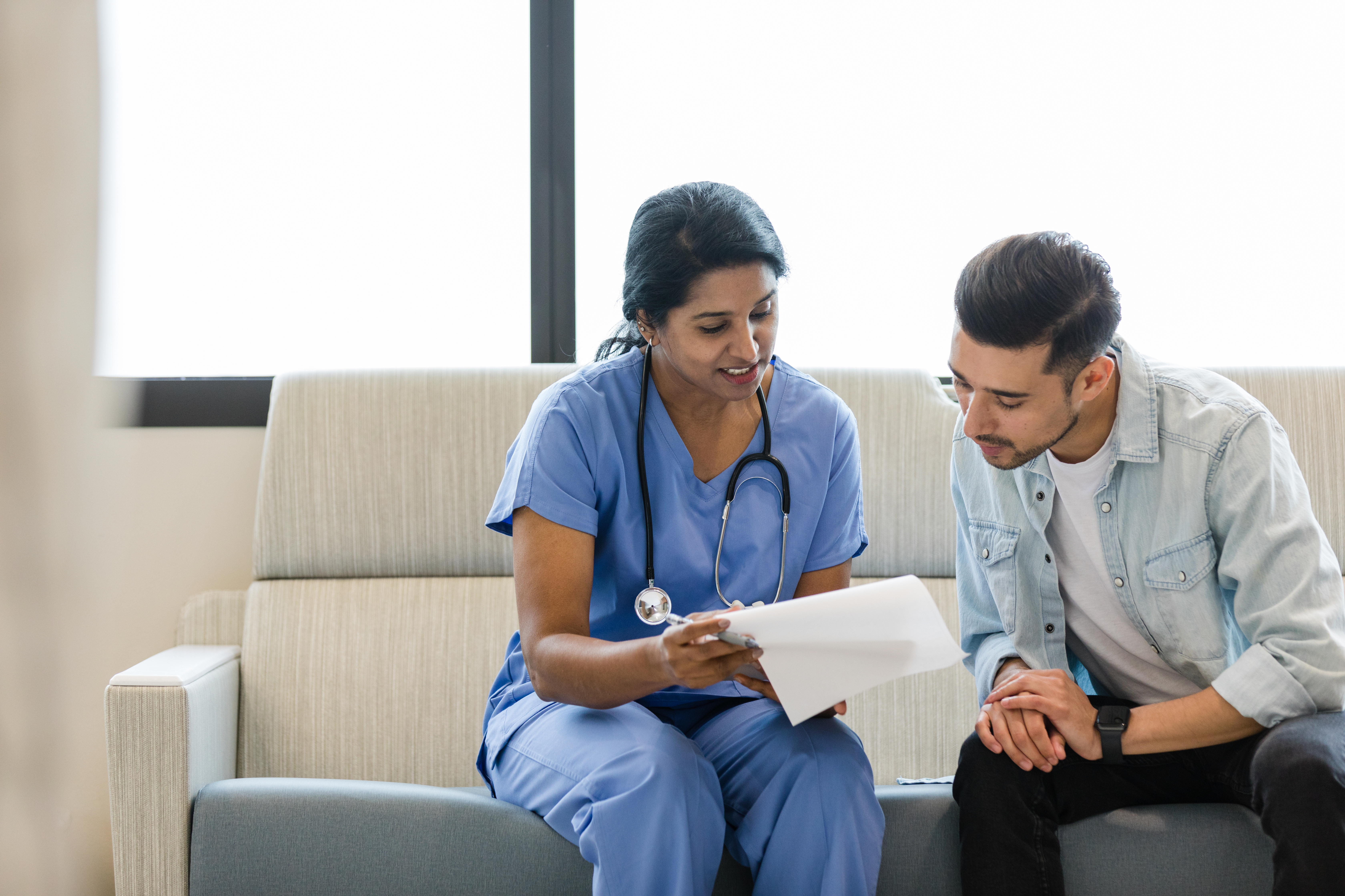 Doctor and patient on sofa with paperwork