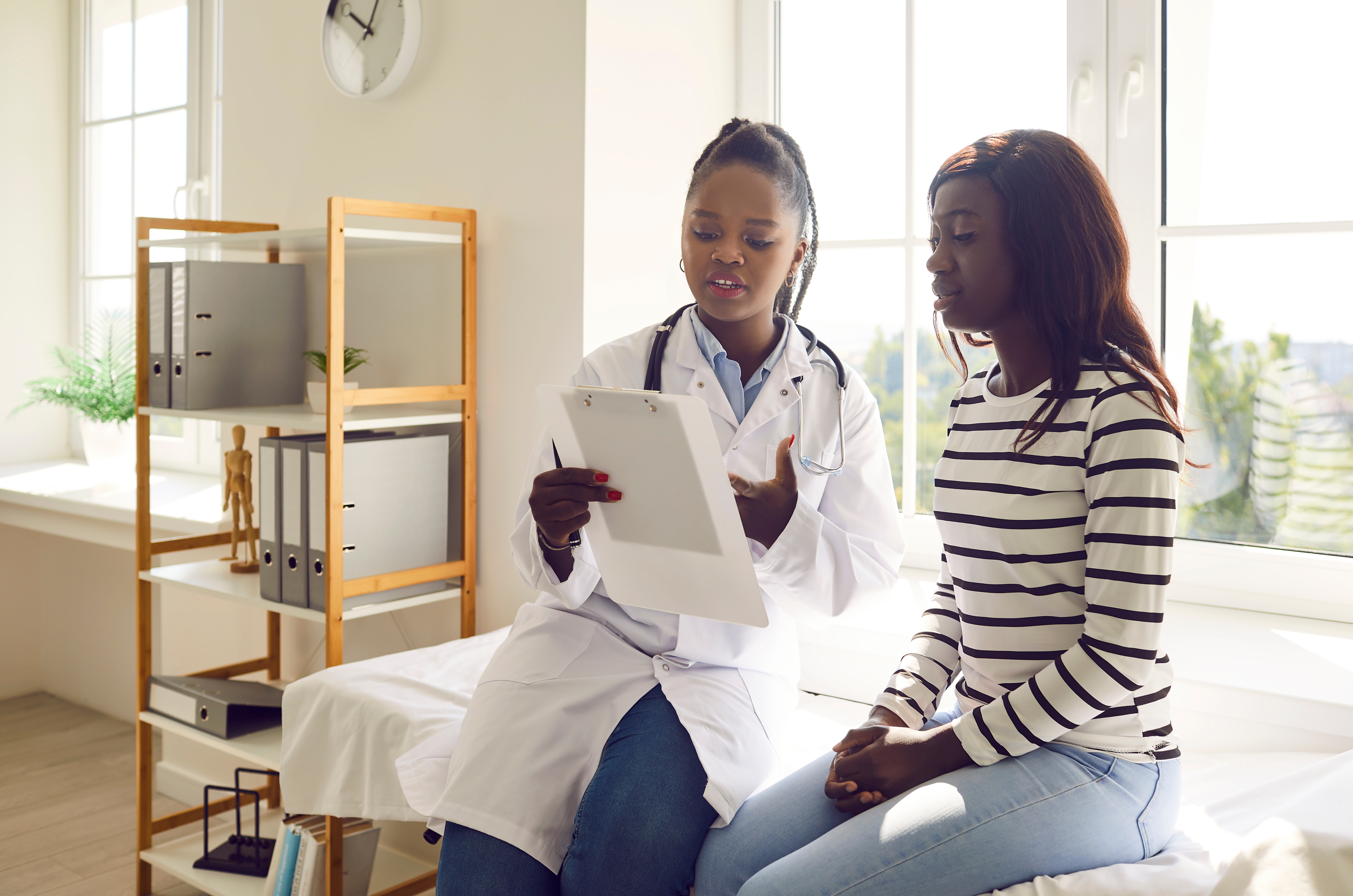Doctor explaining paperwork to patient on a consult bed
